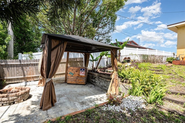 view of patio featuring a gazebo, a fenced backyard, and an outdoor fire pit