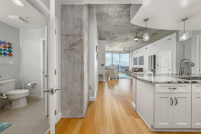 155 S Court Ave Unit 1305, Orlando, FL 32801 - kitchen featuring pendant lighting, light stone countertops, a sink, open floor plan, and white cabinetry