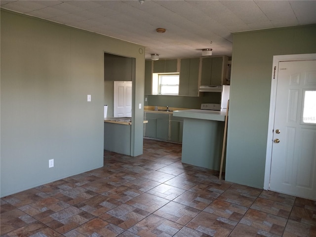 kitchen featuring light countertops, under cabinet range hood, and a sink