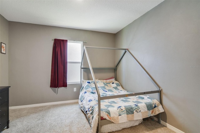 bedroom with carpet flooring, baseboards, and a textured ceiling