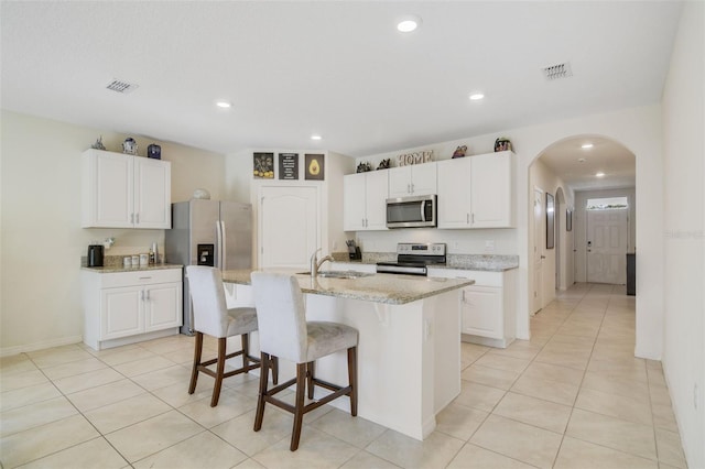 kitchen with appliances with stainless steel finishes, a breakfast bar, white cabinetry, and recessed lighting