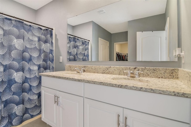 bathroom featuring double vanity, a spacious closet, and tile patterned floors