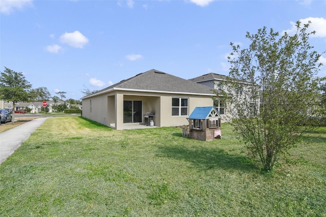 back of house featuring stucco siding and a yard