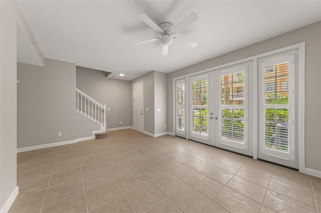 empty room featuring stairs, light tile patterned floors, baseboards, french doors, and a ceiling fan