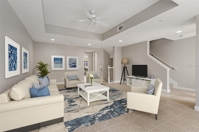 living room with arched walkways, a ceiling fan, recessed lighting, light tile patterned floors, and a raised ceiling