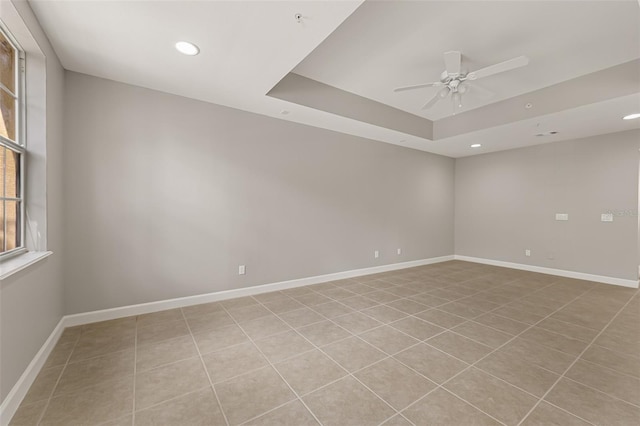unfurnished room with a ceiling fan, recessed lighting, baseboards, a tray ceiling, and light tile patterned floors