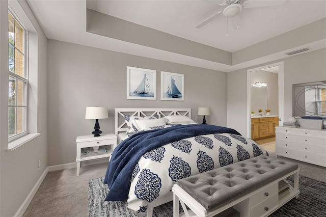 bedroom with light carpet, baseboards, multiple windows, and ensuite bathroom