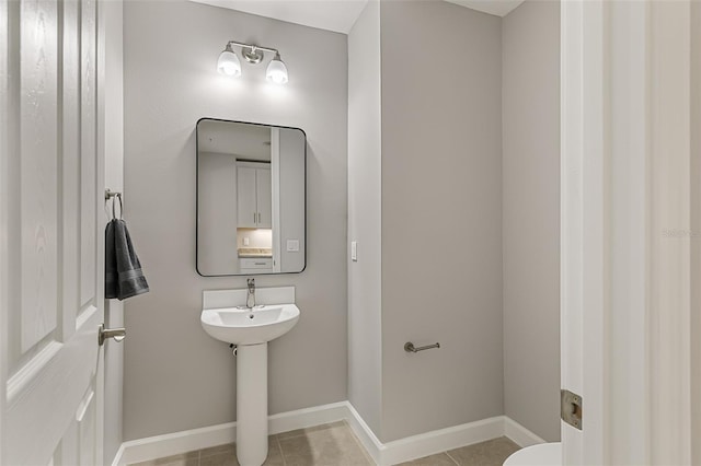 bathroom with baseboards, tile patterned floors, and toilet