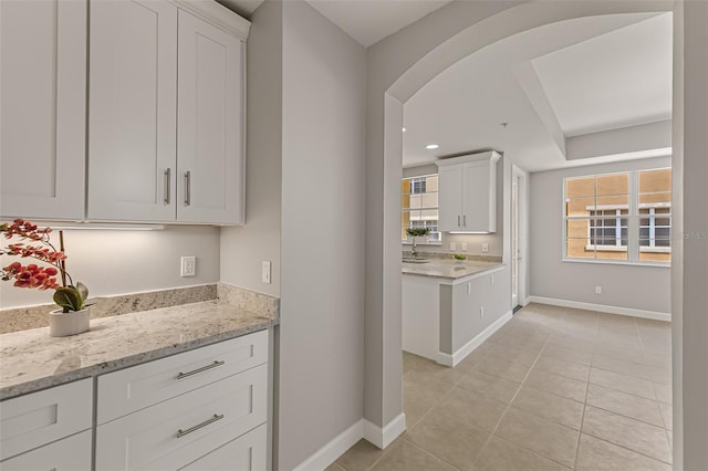 724 Greybull Run, Lake Mary, FL 32746 - kitchen with baseboards, white cabinetry, light tile patterned floors, light stone countertops, and arched walkways