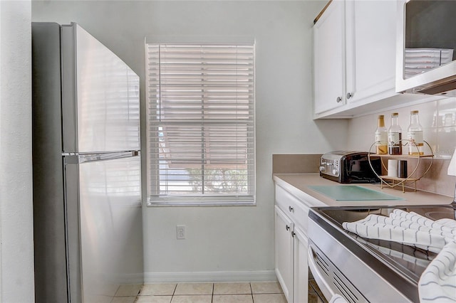 1041 Park Ridge Cir, Kissimmee, FL 34746 - kitchen with light tile patterned floors, baseboards, white cabinets, a toaster, and stainless steel appliances