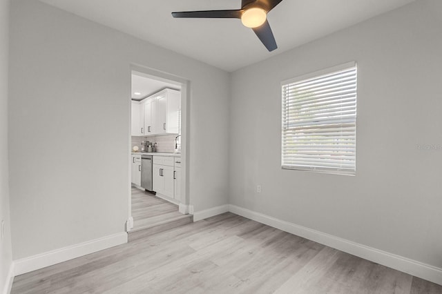 empty room with baseboards, ceiling fan, and light wood-style floors