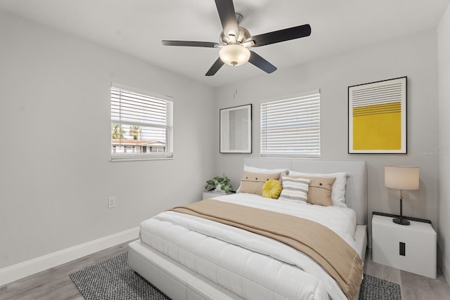 bedroom with a ceiling fan, baseboards, and wood finished floors