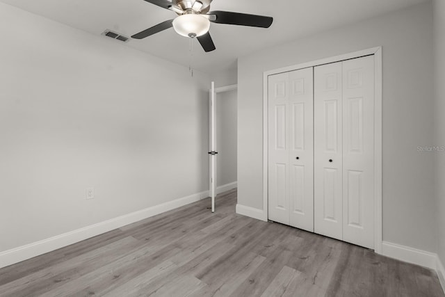 unfurnished bedroom featuring a ceiling fan, baseboards, wood finished floors, visible vents, and a closet