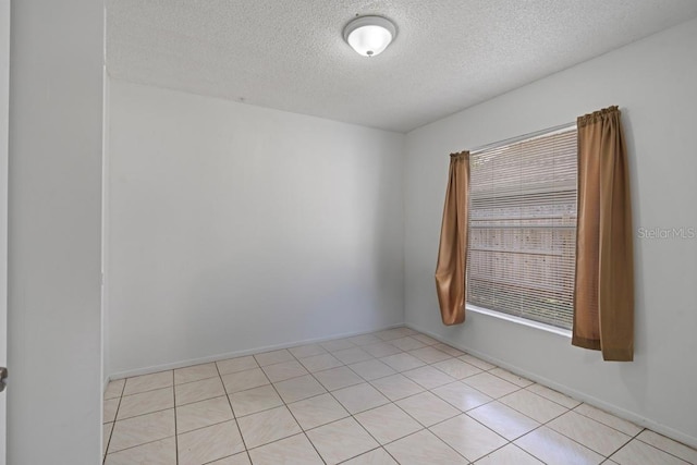 unfurnished room with a textured ceiling and light tile patterned floors