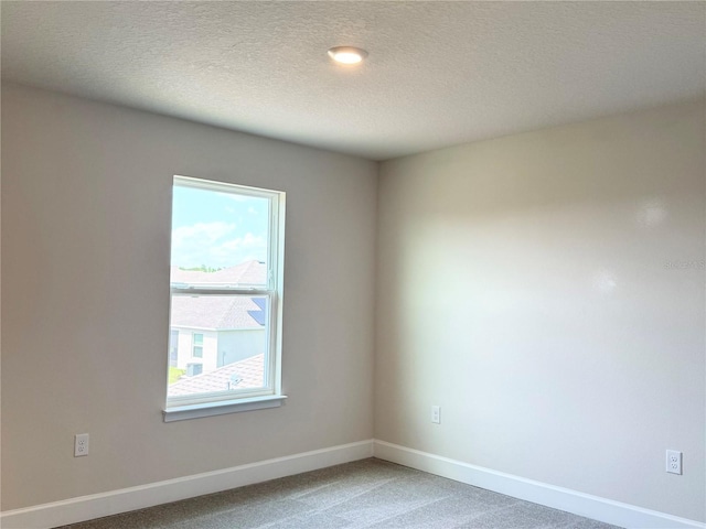 carpeted empty room with baseboards and a textured ceiling