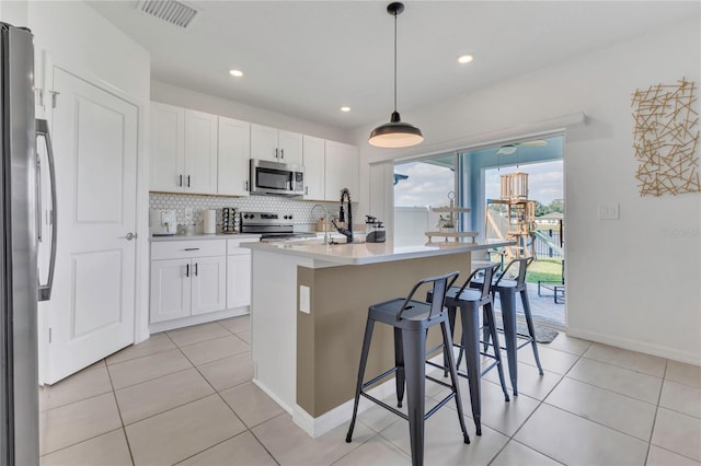 1312 Axel Graeson Ave, Kissimmee, FL 34744 - kitchen featuring visible vents, white cabinets, backsplash, light tile patterned floors, and stainless steel appliances
