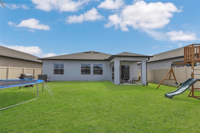 1312 Axel Graeson Ave, Kissimmee, FL 34744 - back of house featuring a ceiling fan, a trampoline, a fenced backyard, a playground, and stucco siding