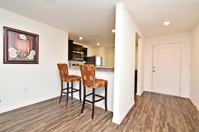 35734 Rose Moss Ave, Leesburg, FL 34788 - kitchen featuring dark wood-type flooring, baseboards, a kitchen breakfast bar, and stainless steel appliances