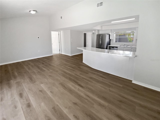 unfurnished living room featuring baseboards, wood finished floors, and visible vents