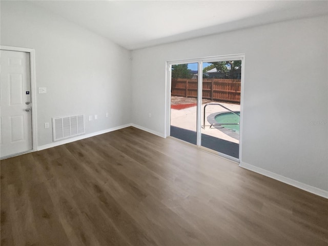 unfurnished room featuring baseboards, visible vents, and wood finished floors