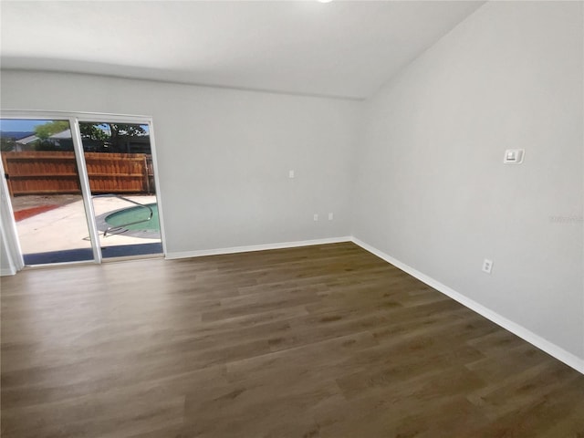 spare room featuring baseboards, vaulted ceiling, and wood finished floors