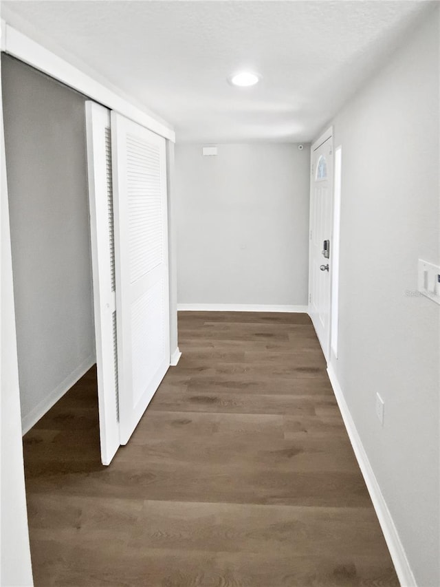 hallway featuring baseboards, recessed lighting, and wood finished floors