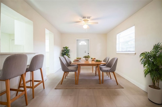 dining area featuring baseboards, visible vents, ceiling fan, and a wealth of natural light