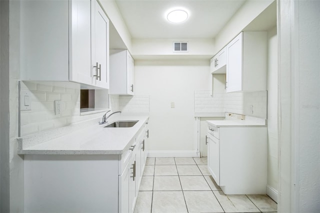 kitchen featuring decorative backsplash, visible vents, a sink, light tile patterned floors, and white cabinets