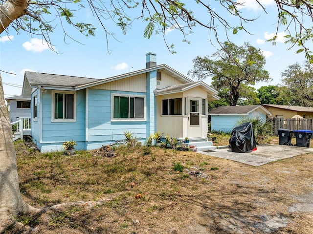 bungalow with entry steps, a chimney, and a patio area