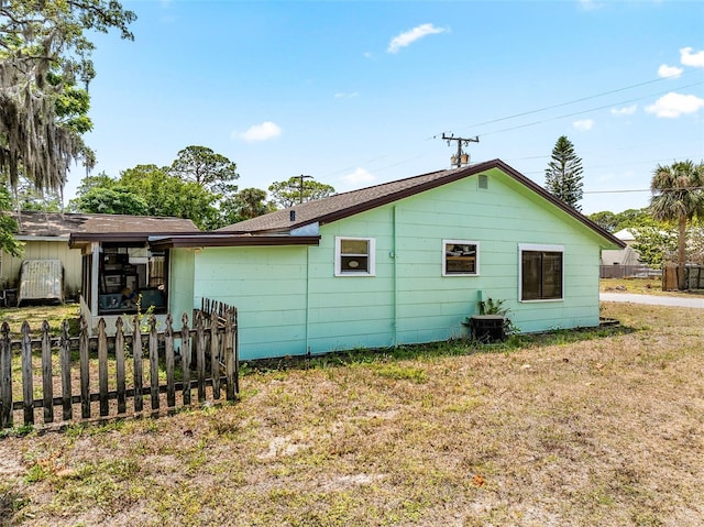 view of property exterior with a lawn and fence