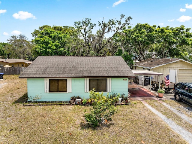 single story home featuring fence, a shingled roof, a front yard, and dirt driveway