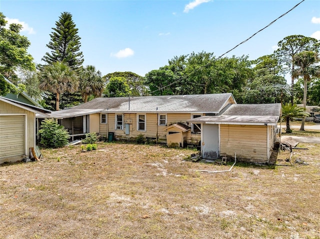 rear view of house with a storage unit, an outbuilding, and a sunroom