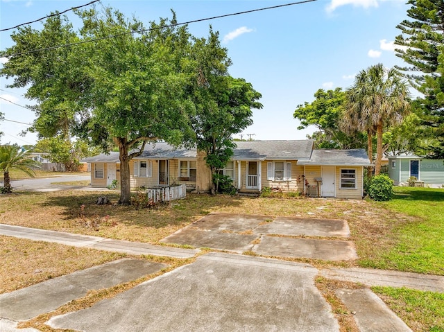 ranch-style home featuring covered porch and a front yard