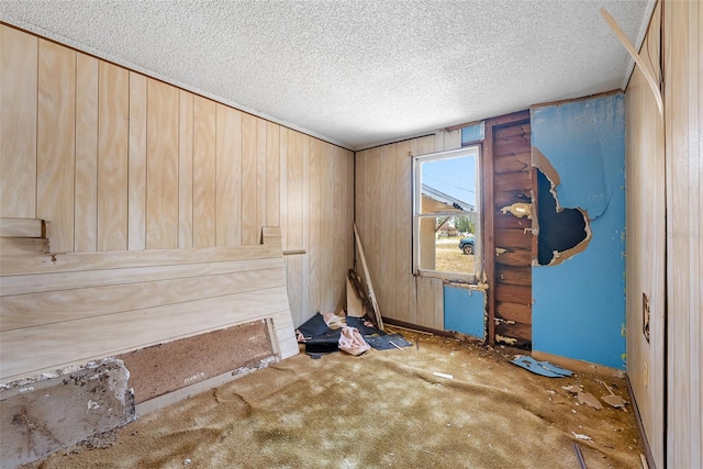 interior space featuring wooden walls, a textured ceiling, and carpet floors
