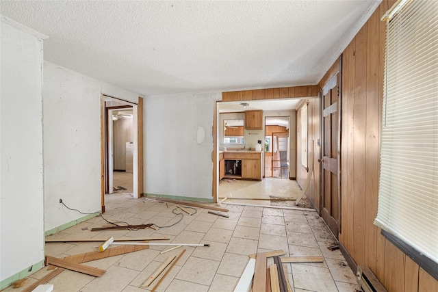 spare room with a sink, a textured ceiling, and wooden walls