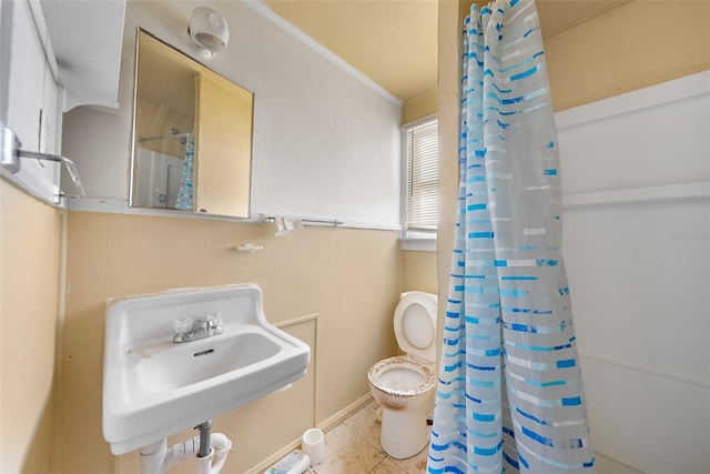 full bath featuring toilet, a shower with curtain, ornamental molding, and a sink