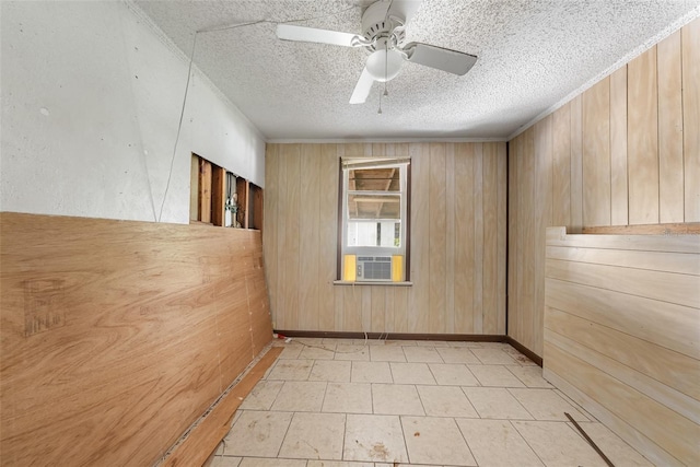 empty room featuring a ceiling fan, wood walls, and a textured ceiling