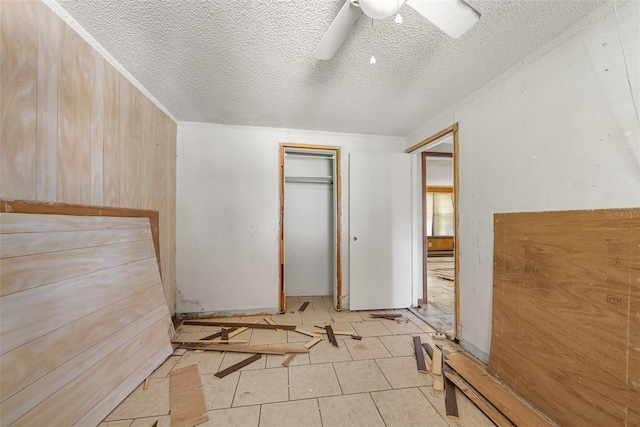 unfurnished bedroom featuring a closet, a textured ceiling, ceiling fan, and light tile patterned floors