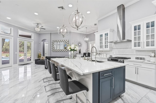1450 Belfiore Way, Windermere, FL 34786 - kitchen with wall chimney range hood, french doors, recessed lighting, white cabinetry, and arched walkways