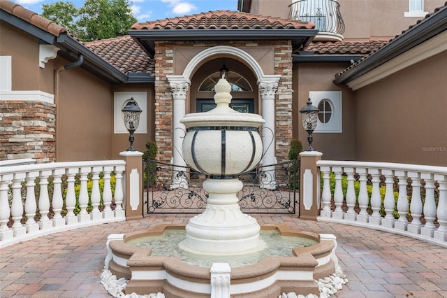 1450 Belfiore Way, Windermere, FL 34786 - view of exterior entry with a tiled roof, stucco siding, stone siding, and a porch