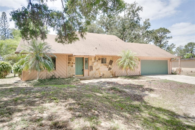 ranch-style home with an attached garage, concrete driveway, and stone siding