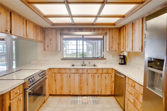 kitchen with light countertops, stainless steel appliances, a sink, and a peninsula