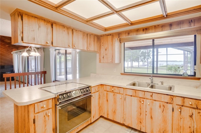 kitchen with electric range, a peninsula, light brown cabinetry, light countertops, and a sink