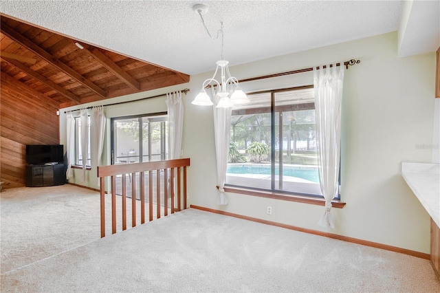 unfurnished dining area featuring an inviting chandelier, carpet floors, baseboards, and wood ceiling