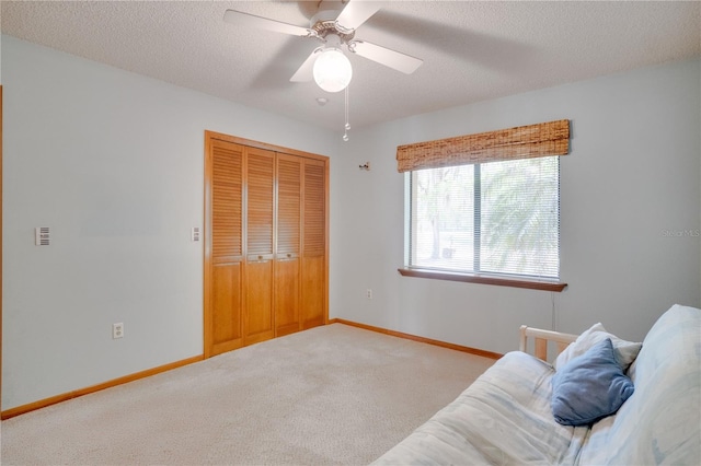 sitting room featuring carpet floors, baseboards, a textured ceiling, and ceiling fan