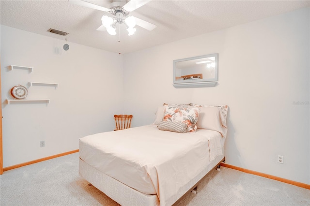 carpeted bedroom featuring a textured ceiling, baseboards, visible vents, and ceiling fan