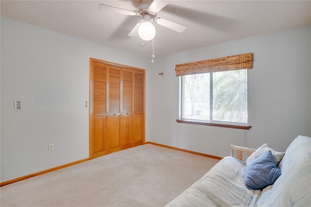 sitting room featuring carpet floors, a ceiling fan, baseboards, and a textured ceiling