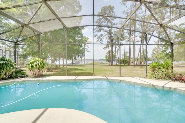 outdoor pool featuring glass enclosure and a lawn