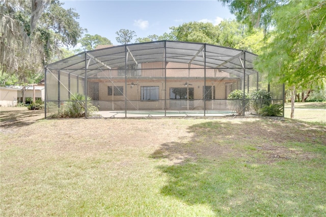 rear view of property featuring a lawn, an outdoor pool, and a lanai