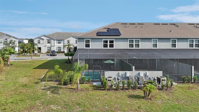 7554 Oak Spring Ln, Davenport, FL 33837 - rear view of property with roof mounted solar panels, an outdoor pool, a yard, glass enclosure, and central AC unit